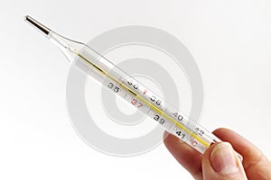 Hand with glass mercury thermometer with celsius degree. Thermometer close-up on white background. Health temperature concept