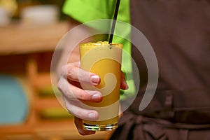 Hand with glass of orange juice. Waiter sercing a glass of fresh fruit juice in a restaurant. Waiter at work.