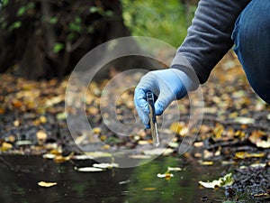 Hand in glove collects water from a puddle in a test tube. Analysis of water purity, environment, ecology - concept