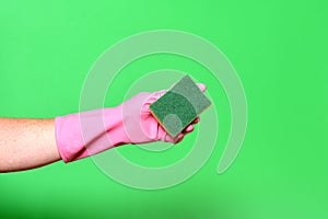 Hand with glove hoding scourer on green background photo