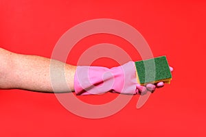 Hand with glove hoding scourer on red background photo