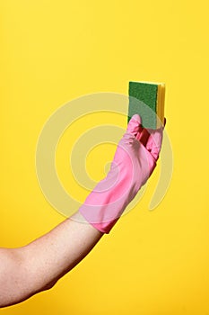 Hand with glove hoding scourer on yellow background photo