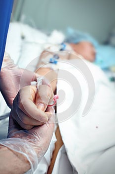 Hand in glove holding a carefully a patient in ICU