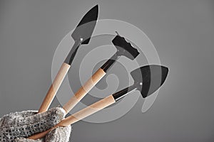 Hand in a glove holding gardening tools  on gray background.