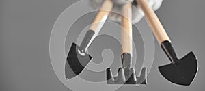 Hand in a glove holding gardening tools  on gray background. Photo with copy space.