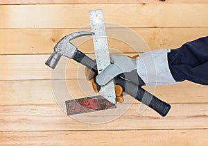 Hand in glove holding iron ruler and hammer