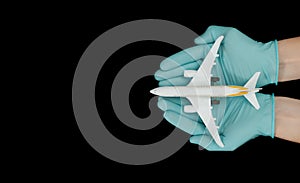Hand in glove holding model airplanes on black background. Concept traveling. Copy space