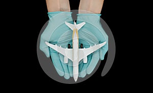 Hand in glove holding model airplanes on black background. Concept traveling. Copy space