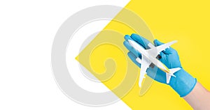 Hand in glove holding model airplanes on yellow background. Concept traveling. Copy space