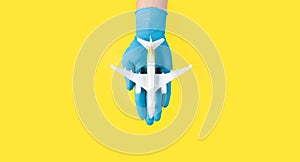 Hand in glove holding model airplanes on yellow background. Concept traveling. Copy space