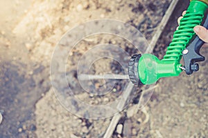 Hand in glove holds watering hose/hand in a rubber protective glove holds a watering, green hose with a green spray nozzle