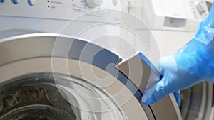 Hand in glove open the door of washing machine for a chemical disinfectant