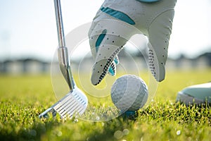 Hand in glove placing golf ball on tee