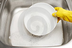 Hand in glove washing plate under running tap water