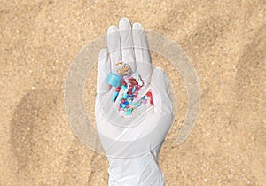 hand in gloved showing microplastics on the beach