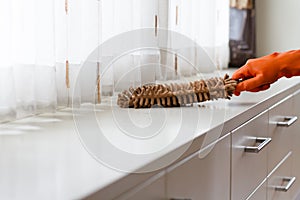 Hand in gloves are cleaning house by wiping dust on desk