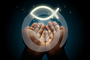 Hand with a glowing ichthys symbol