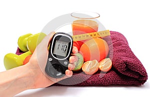 Hand with glucometer, fruits, tape measure, juice and dumbbells