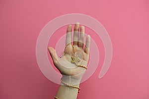 hand with golden bracelet star on a pink backgroun