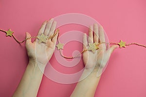 hand with golden bracelet star on a pink backgroun