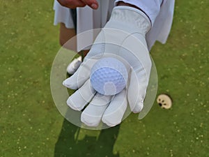 Hand golf glove with white golf ball on green background
