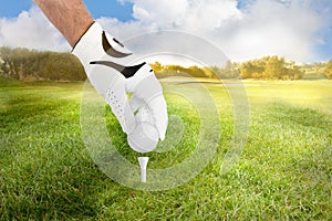 Hand of a golfer places golf ball on the tee on fairway