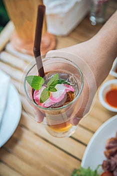 Hand grab ice chinese tea in glass with wood background decorate