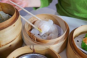 Hand Grabbing a Chinese Shrimp Dumplings Called Ha Gau with Chopsticks