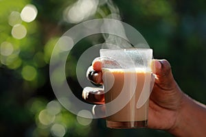 A hand grabbing a glass of tea from a wooden table