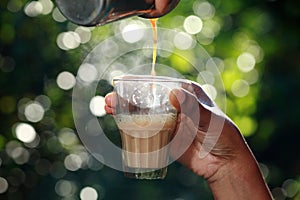 A hand grabbing a glass of tea from a wooden table