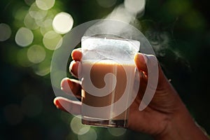 A hand grabbing a glass of tea from a wooden table