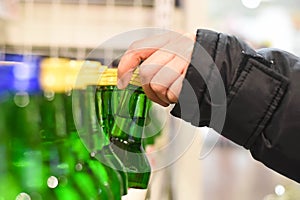 A hand grabbing a green bottle of Korean liquor alcoholic drink at a supermarket.