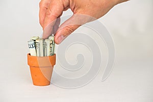 Hand grabbing money in a terracotta pot