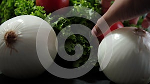 Hand grabbing tomato on top of big fresh lettuce