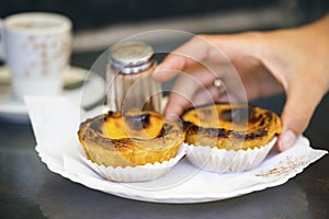 Hand grabbing typical Portuguese pastry - Pastel de Nata. photo