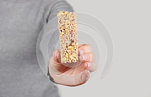 Hand with granola bar on grey background