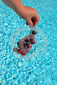 Hand with grapes over water