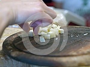 Hand grasping cubes of cheese on a wooden cutting board