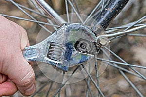 a hand with a gray adjustable wrench tightens a nut on a black frame