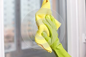 Hand in Green Glove Wiping Window with Microfiber Rag. Professional Cleaning Service