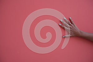 Hand with green nail polish stroking colorful wall