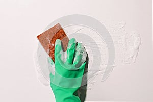 Hand in green rubber glove wiping a foam on the glass, spring cleaning