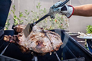 Hand grilling barbecue with big pork at backyard on day