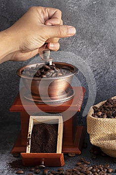 Hand grinding coffee beans in wooden grinder