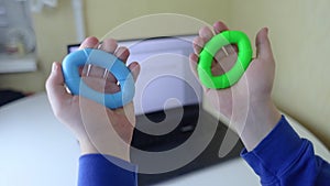 Hand gripper. Man squeezes rubber expander while working on his laptop. Concept of combining useful activity with necessary work.