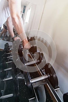 Hand gripping a dumbbell, on a dumbbell bench. Gym. Sports concept