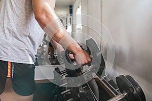 Hand gripping a dumbbell, on a dumbbell bench. Gym. Sports concept