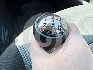 Hand gripping manual gear shift in car interior close-up