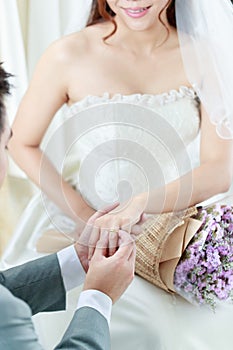 Hand of The groom wears a wedding ring to the bride