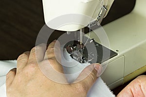 Hand guiding cloth through a sewing machine